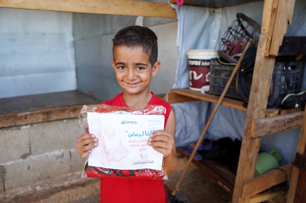 One of Umm Nasser’s sons shows off his clothing packet. Photo by Mohamad Zock.