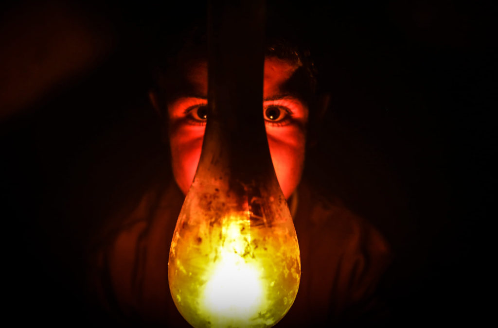 A Palestinian boy uses a gas lamp during a power cut in Gaza.