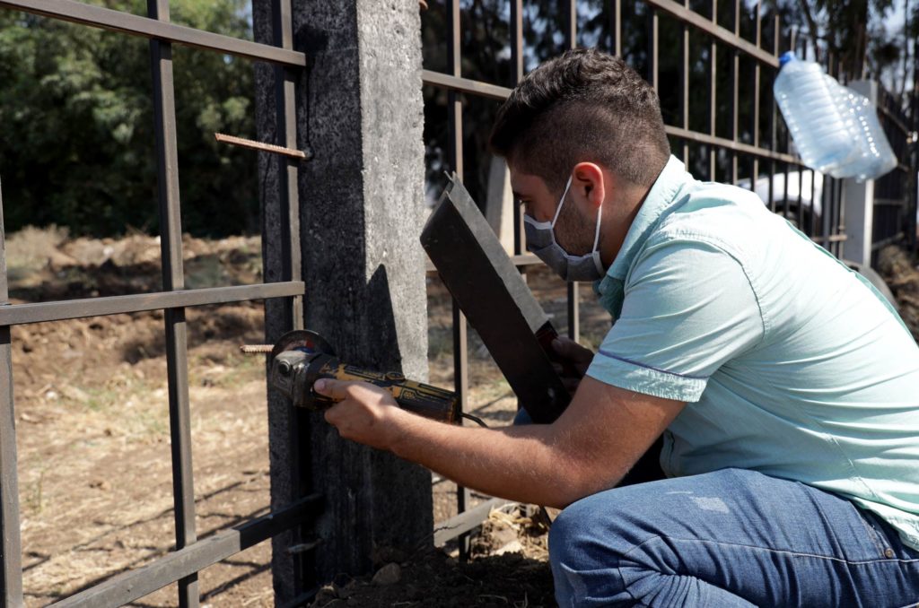 A vocational course student works on a fence post.