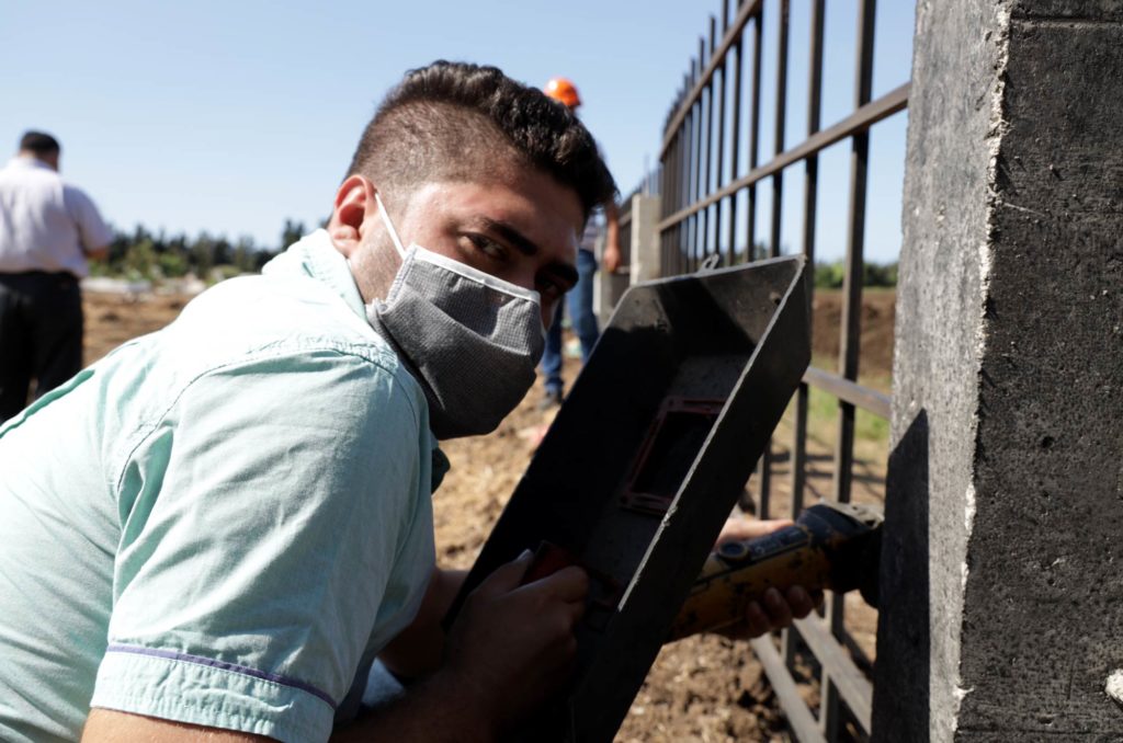 A vocational course construction student works on the cemetery fence.