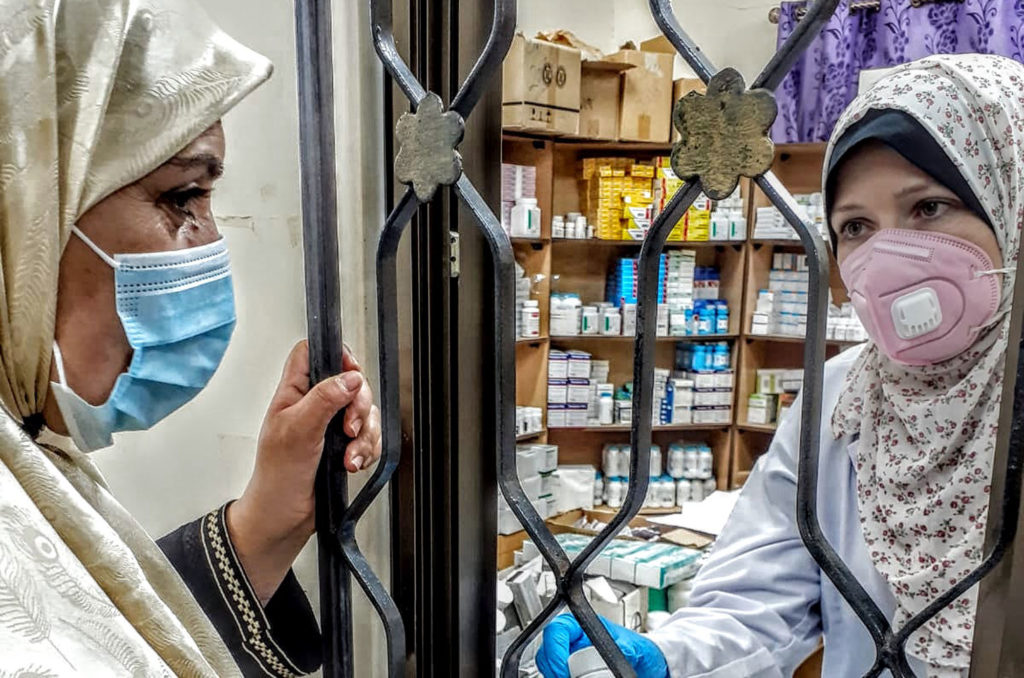 Haja Wafa getting her blood pressure prescription through the pharmacy window.