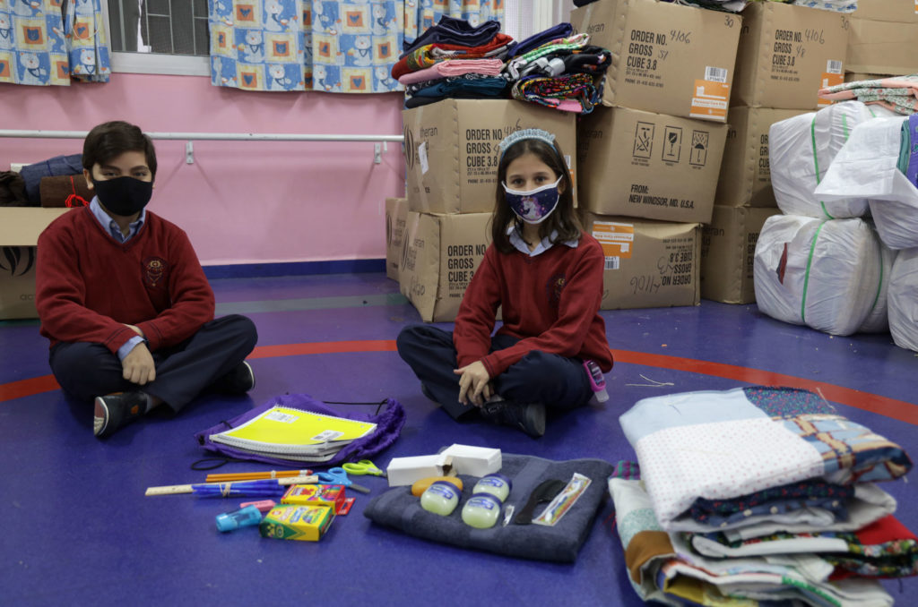 Two schoolchildren with the donated educational and hygiene supplies.