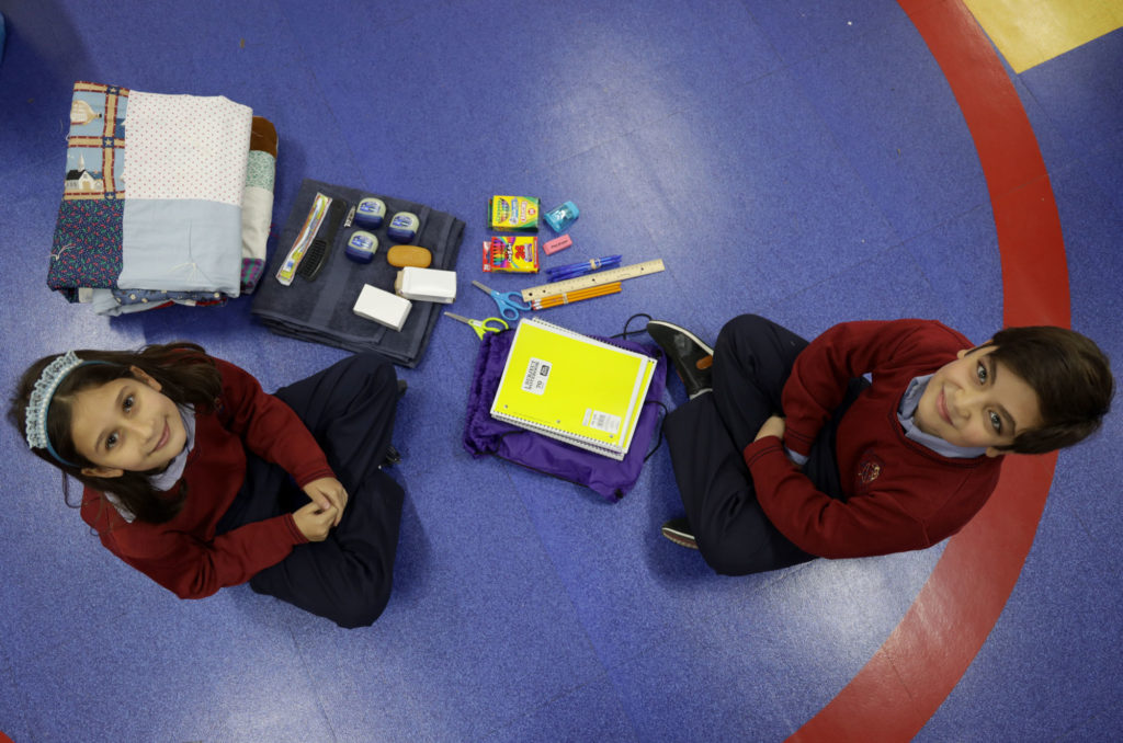 Overhead view of two schoolchildren with the donated educational and hygiene supplies.