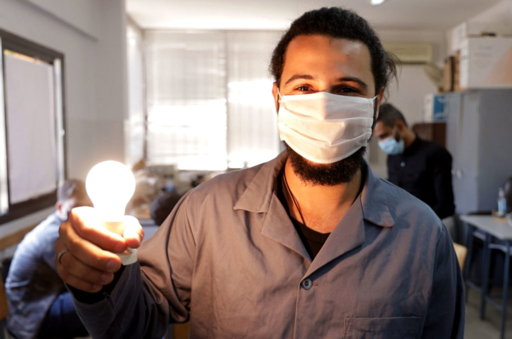A student holds up a glowing light bulb.