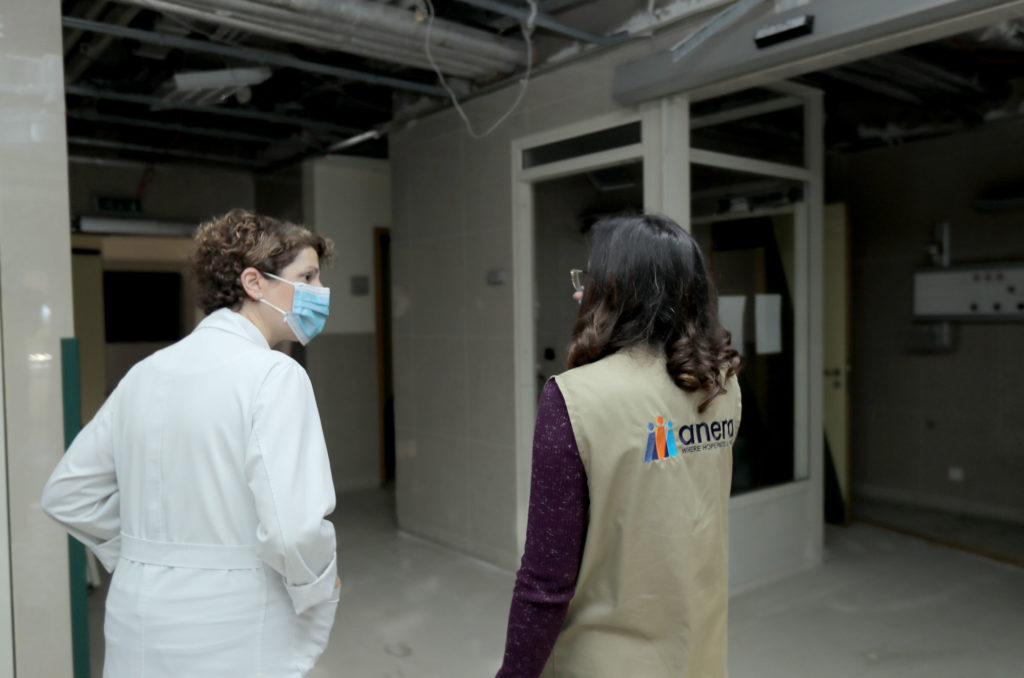 Josiane Kanaan and Anera staff walk through a hospital area under construction.