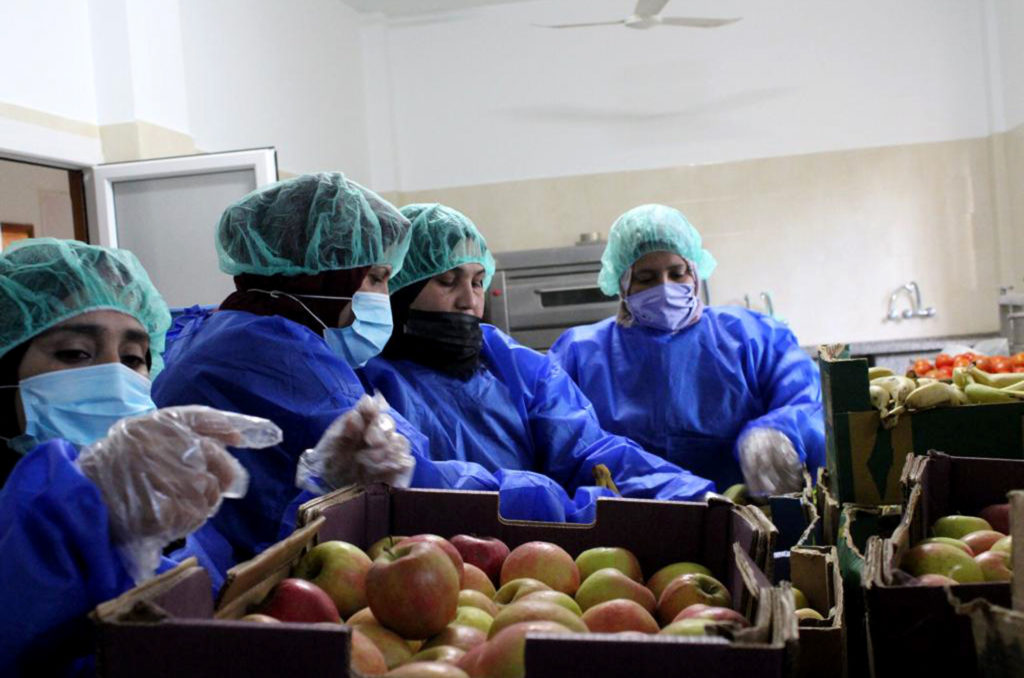 Women unload a crate of apples