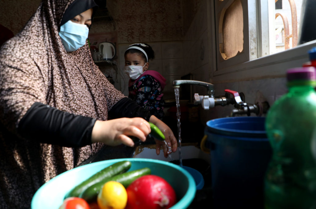 Niveen washes produce in the kitchen sink with her daughter.