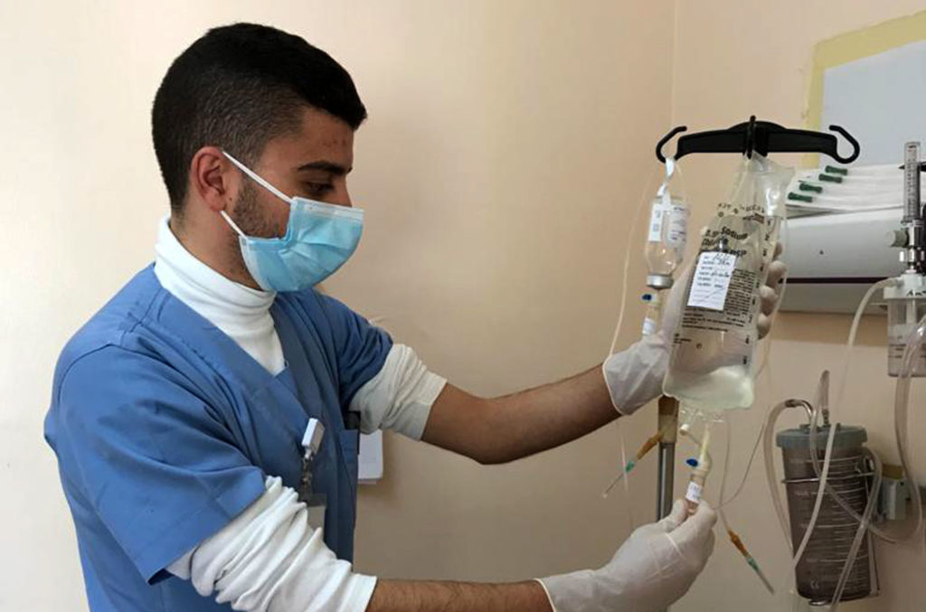 An Al Ahli Hospital technician hooks up a saline drip.