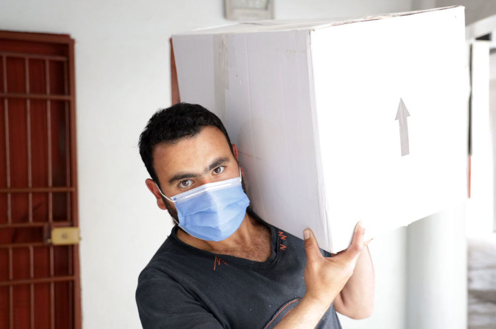 A volunteer hoists a food parcel for delivery