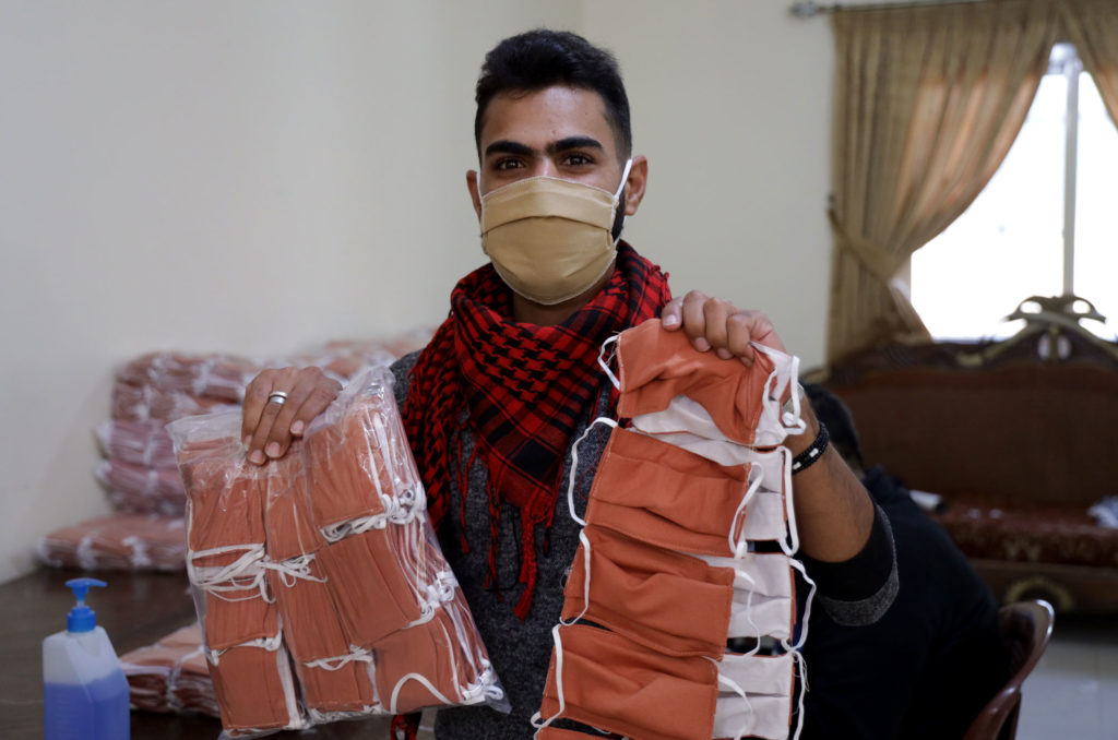 Alaa holds up the finished masks, packaged for distribution.