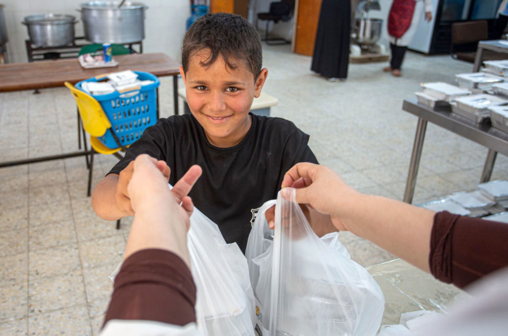 Nine-year-old Islam picks up food for his family, who saw their house destroyed. Islam lives with his parents and younger siblings in Beit Hanoun, in northern Gaza.