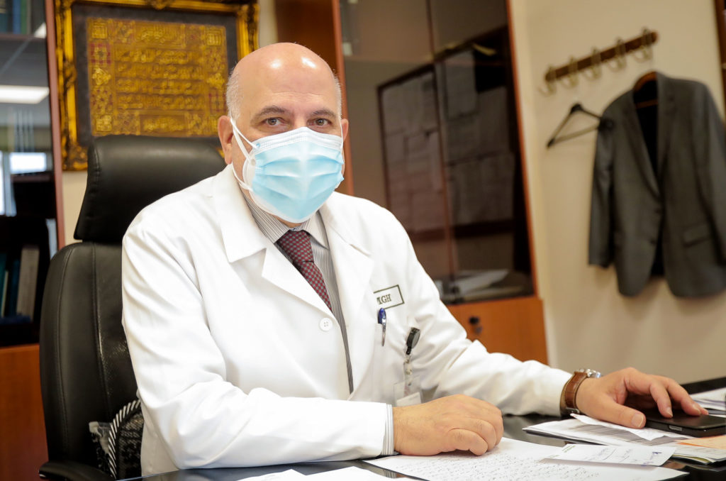 Dr. Hasbini in portrait wearing a mask at his desk.