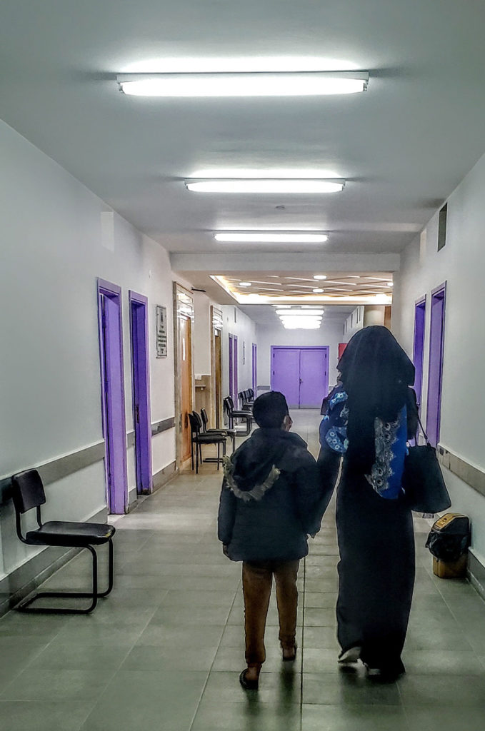 Rafik and his mother walk down the hall