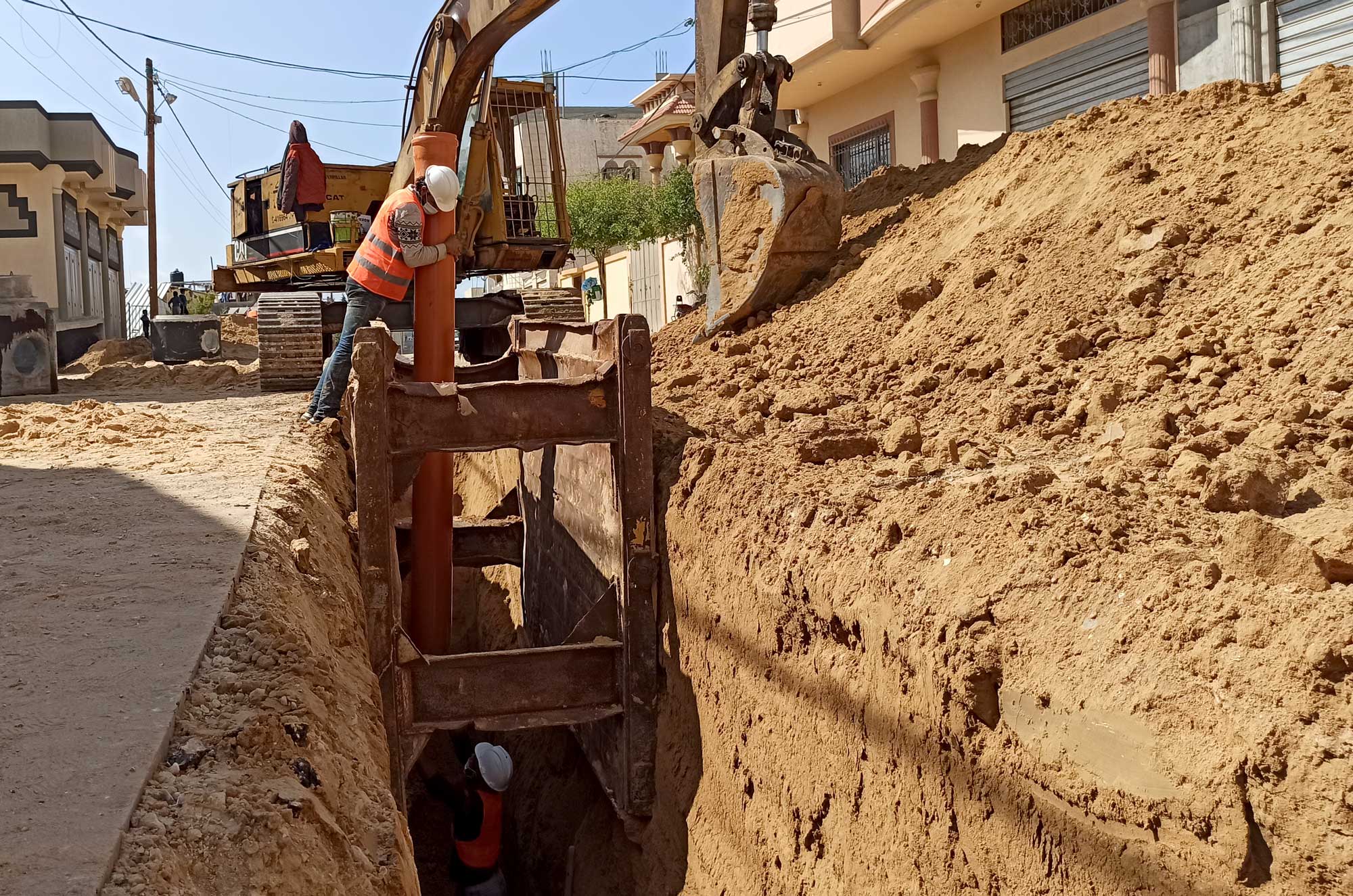 Anera contractors place pipes that will be used to remove waste from homes in Bani Suhaila, Gaza.