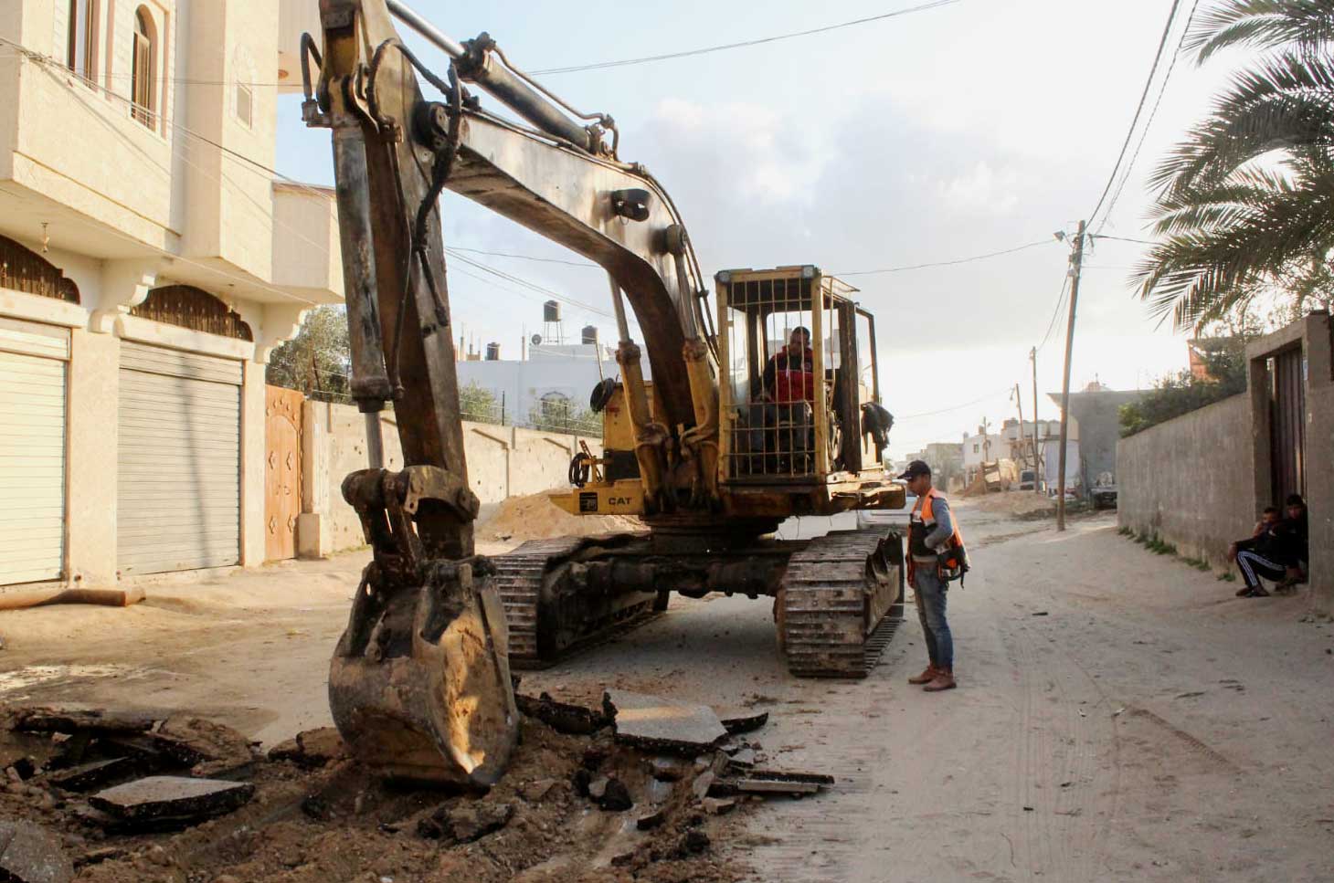 Anera contractors use an excavator to remove the asphalt on a street in Bani Suhaila, Gaza.