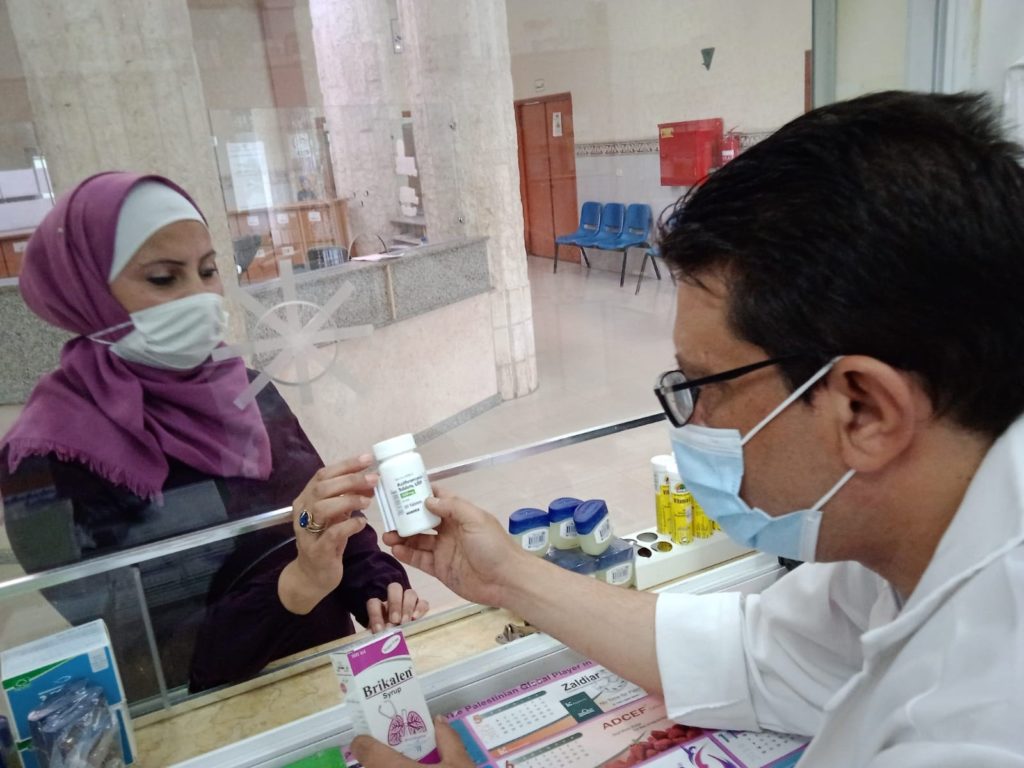 Pharmacist Raed Baraawi at the El Shakhra Association hands azithromycin to a patient.