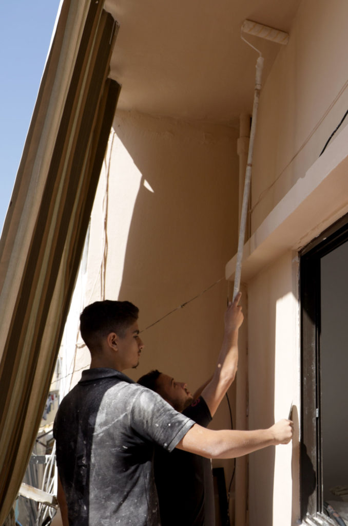 Two young men paint an exterior wall.