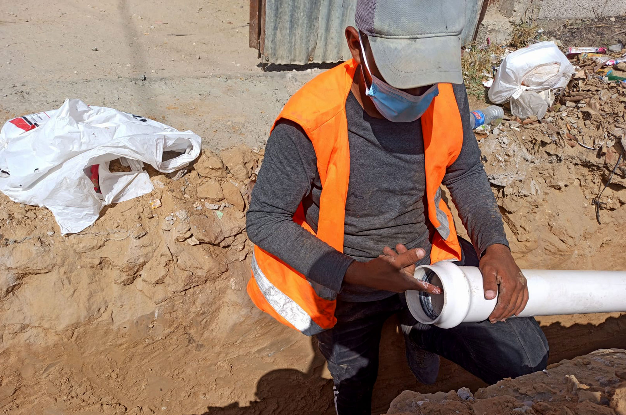 A worker applies a sealant to one end of a pipe segment.