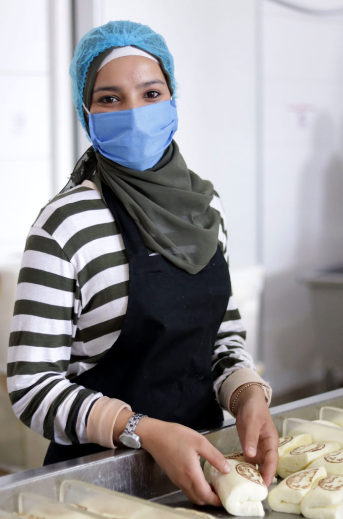 Hasnaa holds blocks of freshly made cheese.