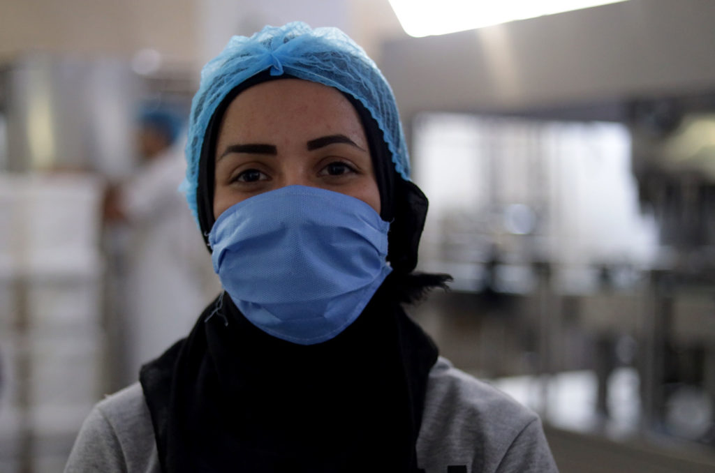 Iman in the dairy facility with hair net and mask on.