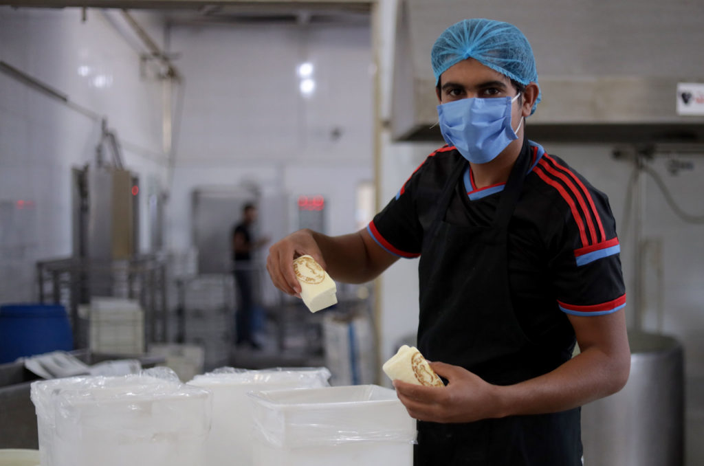 Omar holds two blocks of fresh cheese.