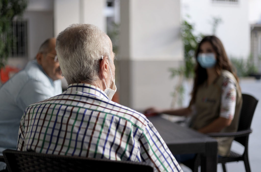 A patient, seen from behind, speaks to Anera.