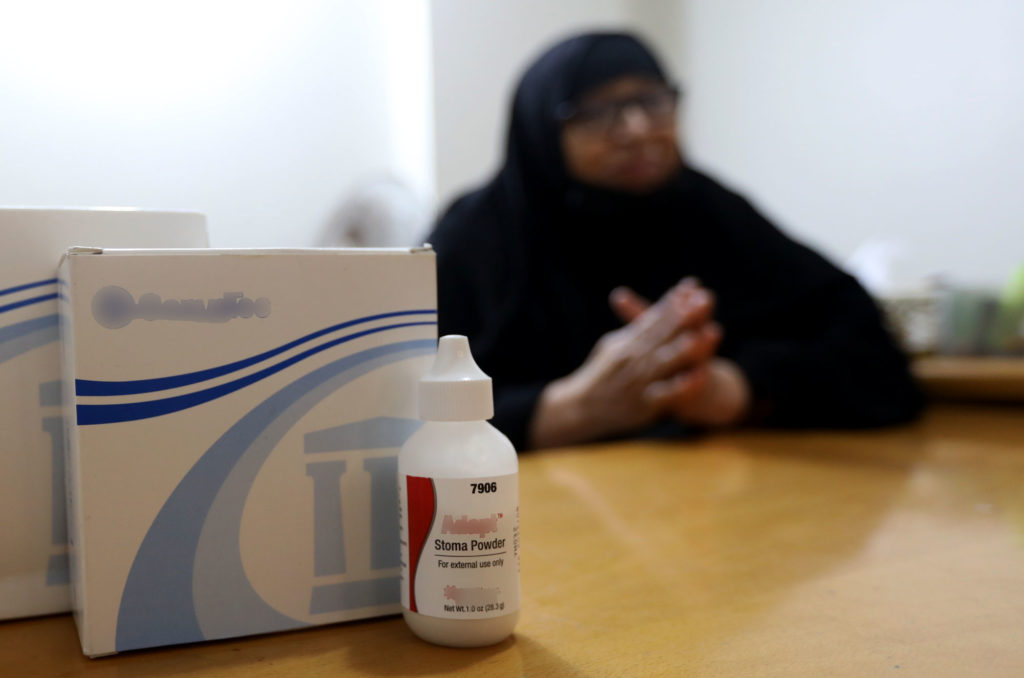 Najah tells her story. Medical supplies sit on the table in the foreground.