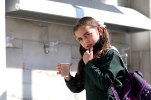 School girl in Gaza drinks water from a tap that Anera installed and connected to a reverse osmosis system.