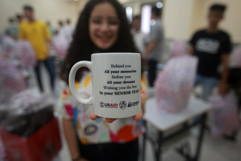 A student at the Rosary School in Gaza holds out her new mug from Anera