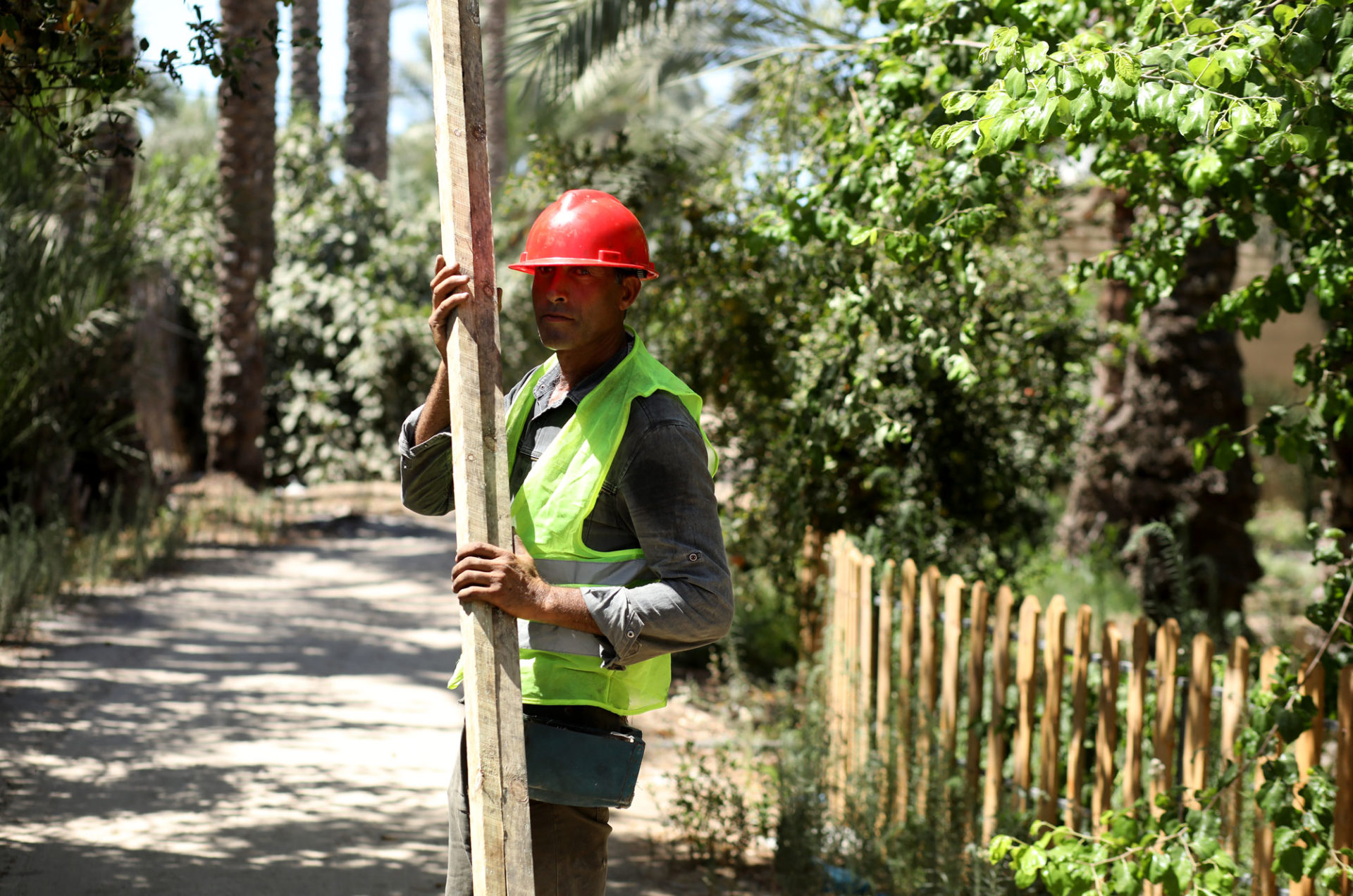 Greenhouse construction worker at the installation site with a length of wood.