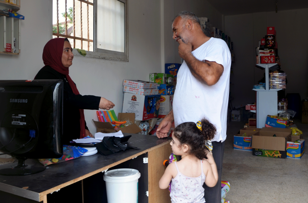 Kawthar helps a customer and his young daughter