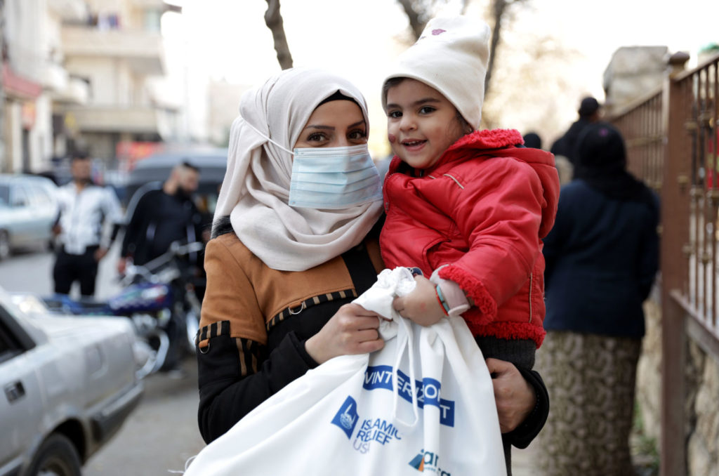 Malak holds her baby daughter and a winterization kit.