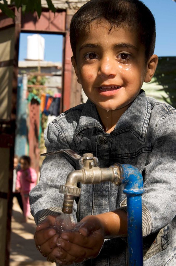 Boy in Musaddar, Gaza washes his hands at a spigot that has running water because of Anera's installation of a reservoir and water network in his village.