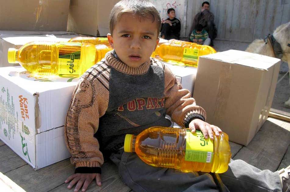 A youngster sits on his family's cart amidst the food items they just received from Anera. 