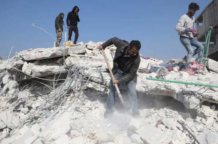 Man digs the rubble of his home in Syria after the February 2023 earthquake.