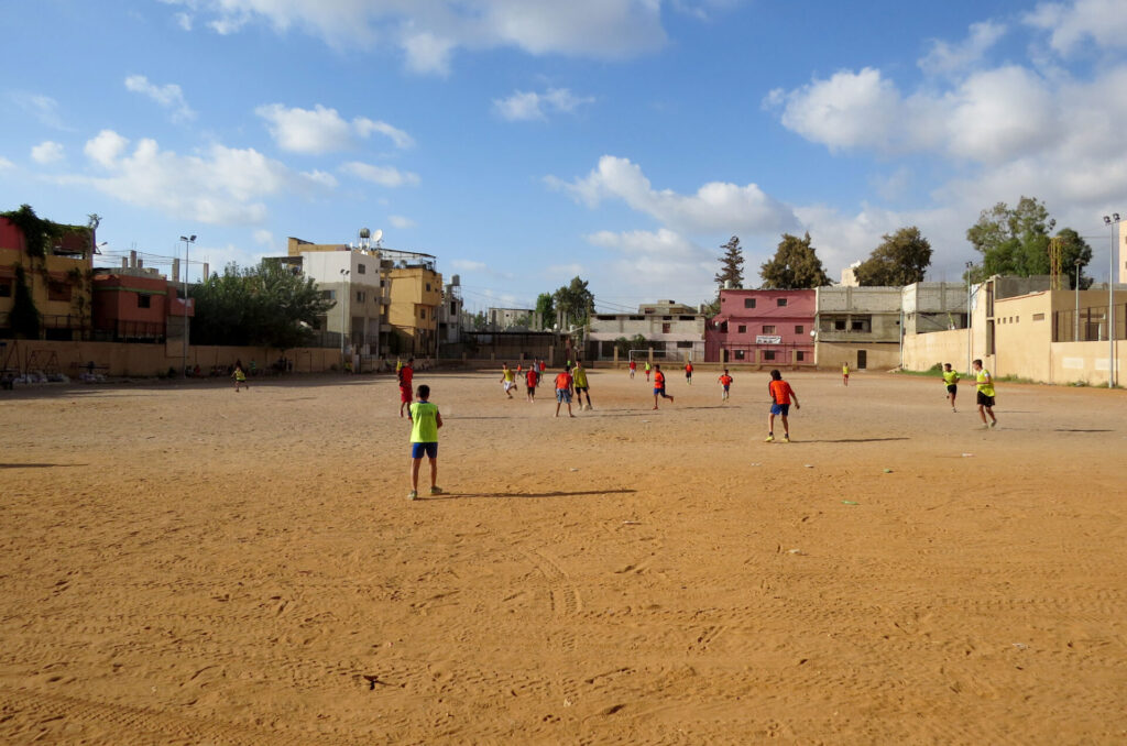 Kids playing on a soccer field in Ein El Hilweh, Lebanon, that Anera upgraded.