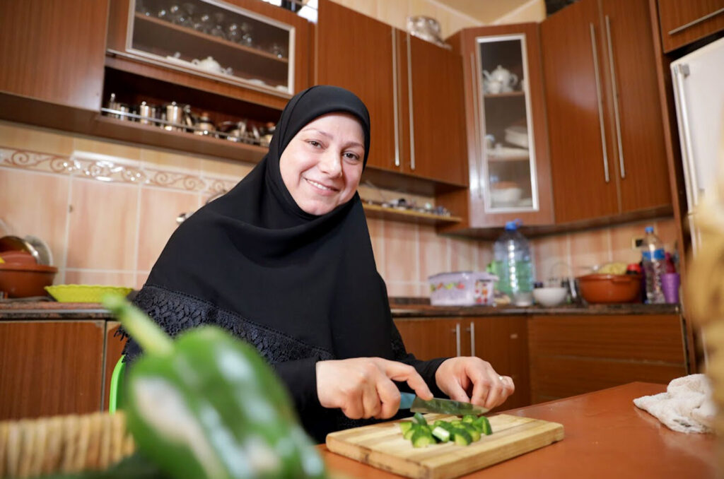 Fadwa in her kitchen chopping produce.