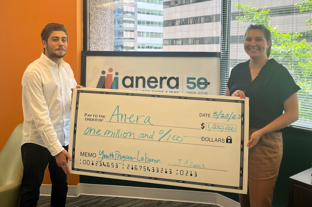 Jad and Haley hold a giant promotional check in the Anera DC office.