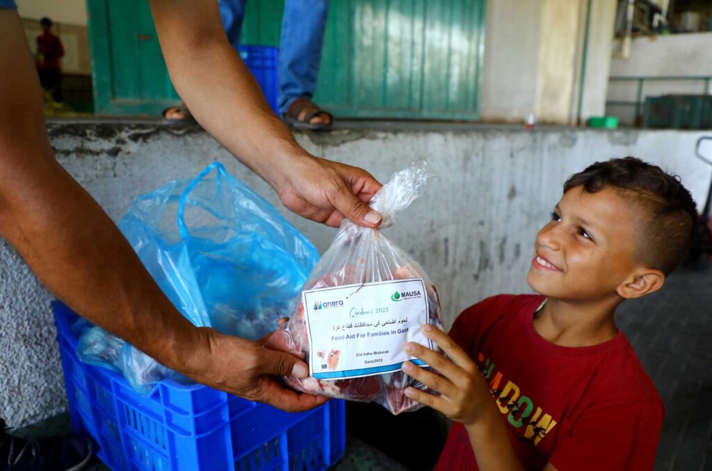 A boy accepts his family's Qurbani package of meat during Anera's distributions in Gaza, 2023.