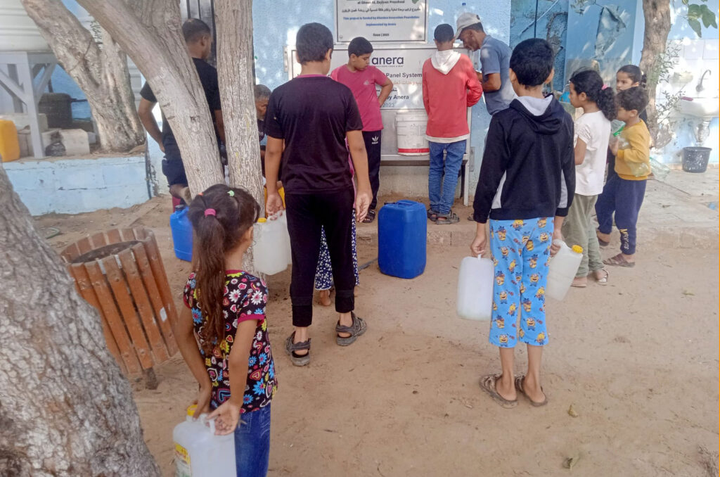 A crowd waits with water canisters to fill them.