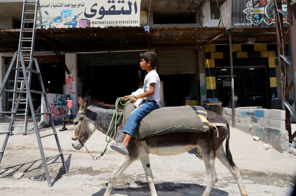 A boy rides a donkey alone through a street in Jerash Camp, Jordan.