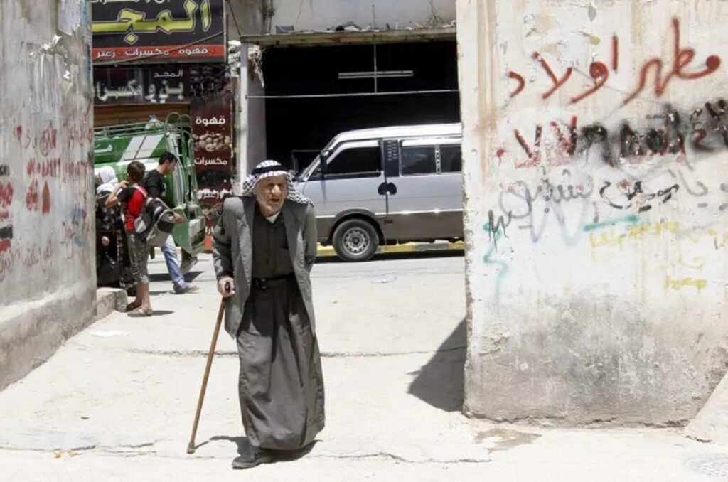 An older man walks through a intersection in Jerash Camp, Jordan.