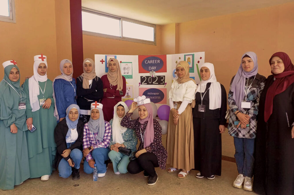 A group of girls stand for a photo wearing components of clothing from different professions, like a nurse's cap.