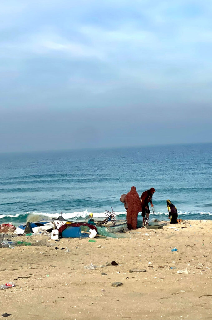Women and children stand by the seashore in Gaza.