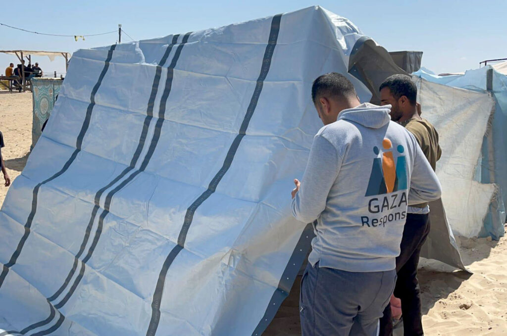 Anera field team installing tarps to provide families sheltering in tent structures with protection from the elements.