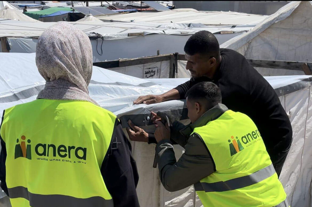 Anera field team installing tarps to provide families sheltering in tent structures with protection from the elements.