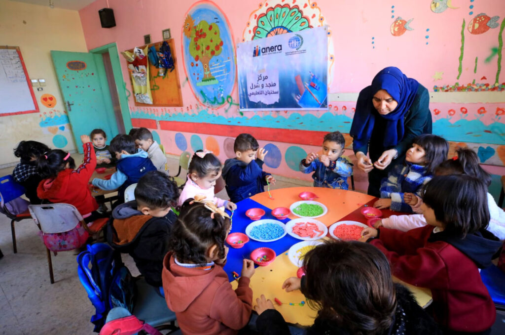 A teacher at one of Anera's temporary learning spaces works with young children in Palestine.