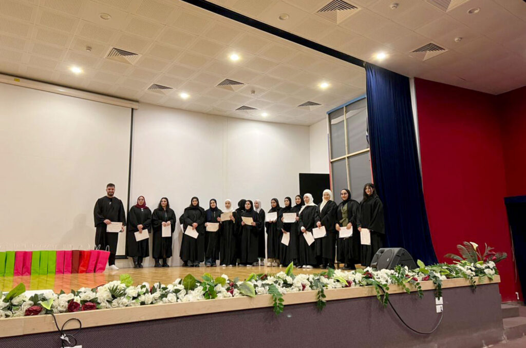 Graduates from Anera's barista course stand on stage with their certificates.