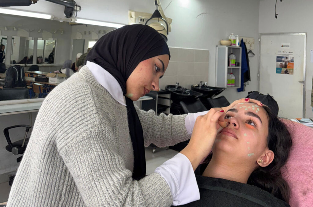 A student in Anera's beauty course practices applying makeup on another student.