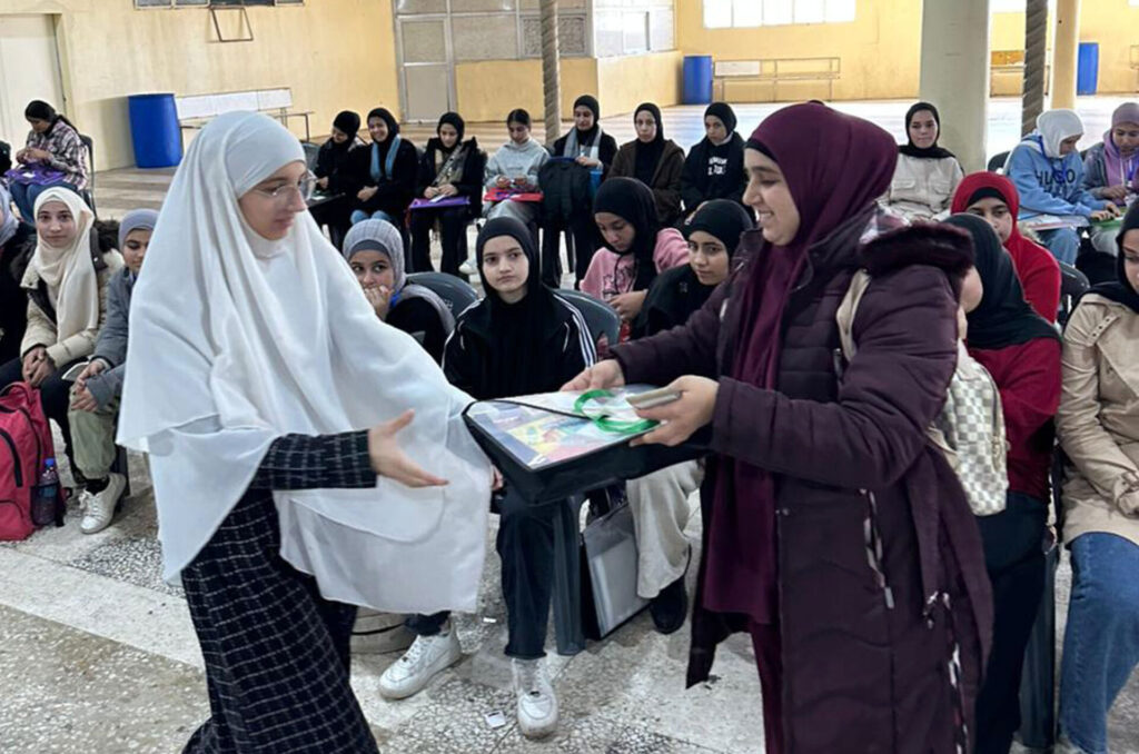 A student receives learning materials in Anera's digital literacy course.